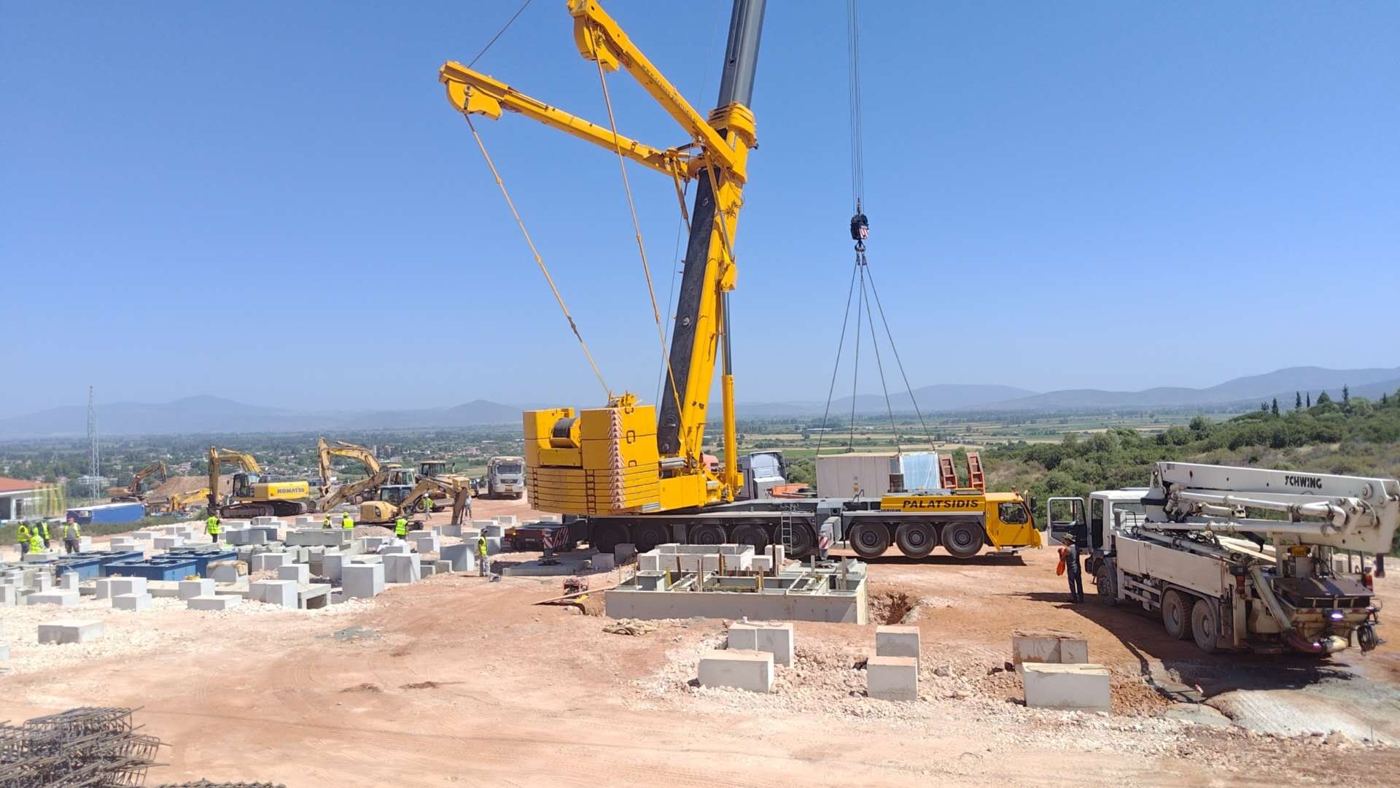 Mobile crane offloading battery storage containers at a project site