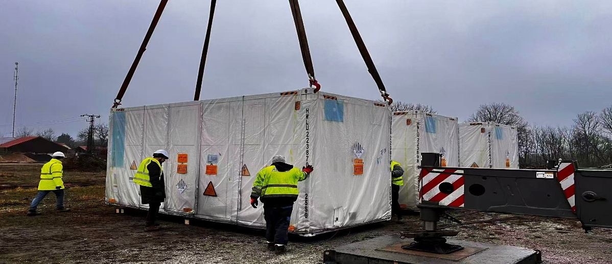 Site team guiding a battery storage container onto its foundation