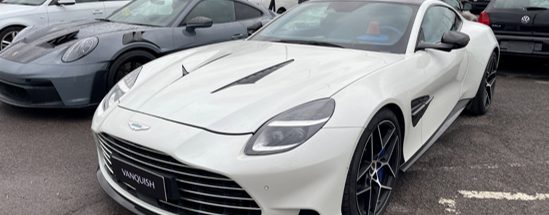 Weißer Aston Martin Vanquish neben anderen Fahrzeugen geparkt